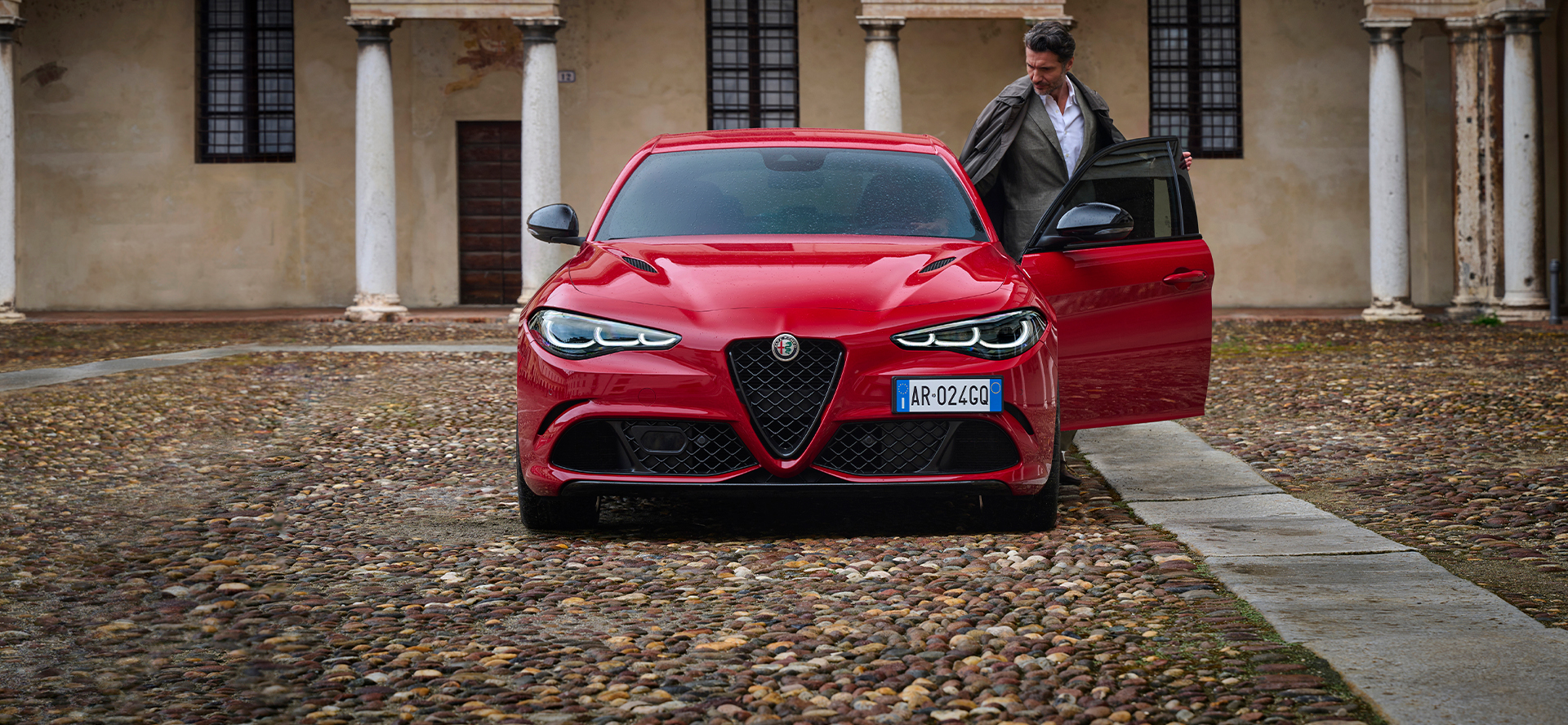 En mann setter seg inn i en rød Giulia