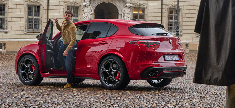 Mann går ut av en rød Stelvio Quadrifoglio