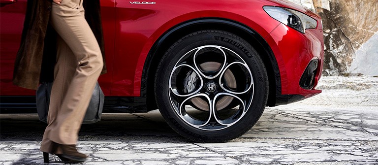 Kvinneben ved siden av fronten med hjulet i fokus på en rød Stelvio