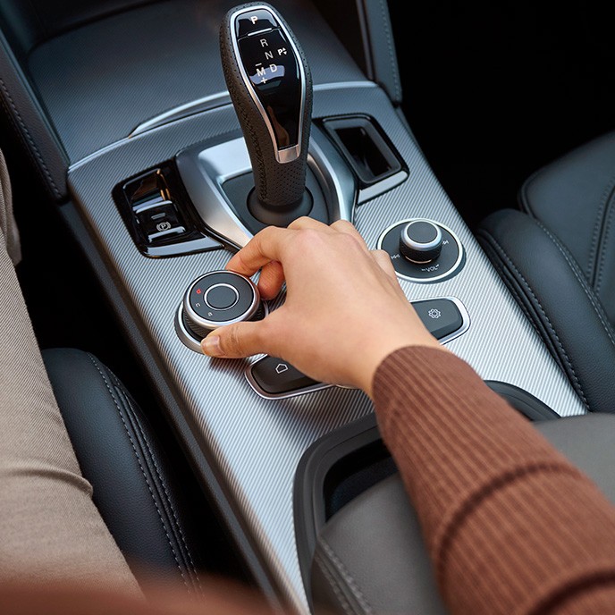 Kvinne vrir på kjøremodusvelger i midskonsoll på en Stelvio
